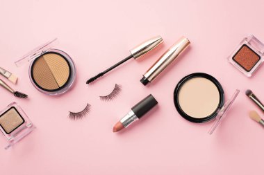 Uydurma konsept. Makyaj fırçaları, makyaj fırçaları, sahte kirpikleri ve pastel pembe arka planda rimel.
