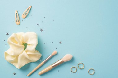 Güzellik konsepti uydur. Moda makyaj fırçalarının, altın tokaların, yıldız şeklinde konfetilerin izole edilmiş pastel mavi arka planda en iyi görüntü fotoğrafı.