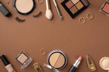 Uydurma konsept. Ruj fotoğrafının üst görüntüsü pudra makyajı sahte kirpikler tırnak cilası, göz farı palet rengi altın yüzükler ve kahverengi arkaplanlı tokalar.