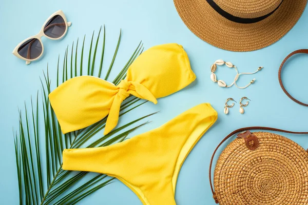 Yaz tatili kavramı. Şapka kabuğundan bileziğin üst görüntüsü küpeler şık güneş gözlükleri sarı bikini yuvarlak rattan çanta ve izole edilmiş pastel arka planda palmiye yaprakları