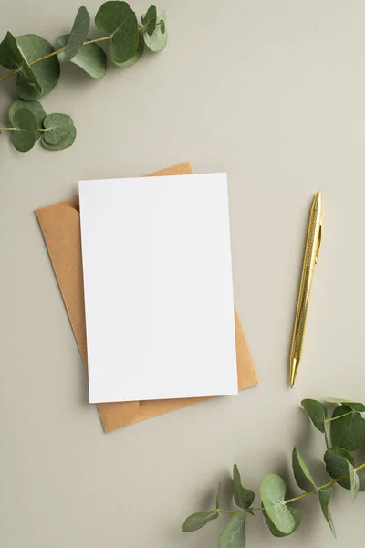 商业概念 纸卡工艺纸包金笔和桉树在空白灰蒙蒙背景上的顶视图垂直照片 — 图库照片