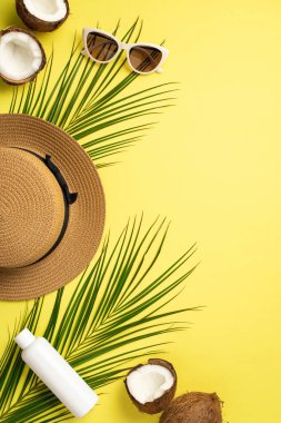 Yaz haftasonu konsepti. Güneş kremi şişesinin dikey görüntüsü Hindistan cevizleri ve sarı arka planda palmiye yaprakları çatladı.