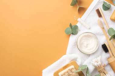 Plastik konsept yok. Diş fırçası kavanozunun üst görüntüsü. Diş macunu beyaz havlu sabunu ile ahşap ayakta duruyor. Pamuk tomurcukları diş ipi ve okaliptüs izole edilmiş turuncu arka planda.