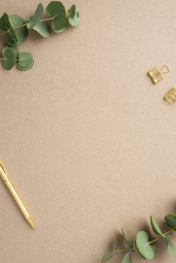 Workstation concept. Top view vertical photo of eucalyptus branches gold pen and binder clips on beige background with copyspace