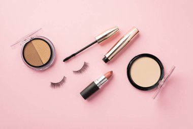 Uydurma konsept. Üst görünüm fotoğraf palet ruj hatlı sahte kirpikler ve pastel pembe arka planda rimel