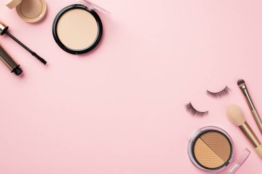 Makyaj güzellik konsepti. Üst görünüm palet sahte kirpikler kompakt toz makyaj fırçaları rimel ve göz farları kopyalama alanı ile pastel pembe arka plan üzerinde