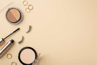 Palet altın halkalarının üst görünüm fotoğrafı sahte kirpikler rimel ve pastel bej arkaplan üzerindeki sıkıştırılmış toz kopyalanmış