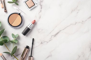 Make-up concept. Top view photo of makeup brushes contouring palette eyeshadow lipstick mascara and eucalyptus on white marble background with empty space