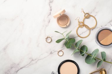 Makyaj konsepti. Beyaz mermer zemin üzerinde şekillendirilmiş palet göz fotografı kompakt toz toz altın küpeler toka ve okaliptüs filizi boş alan arkaplan