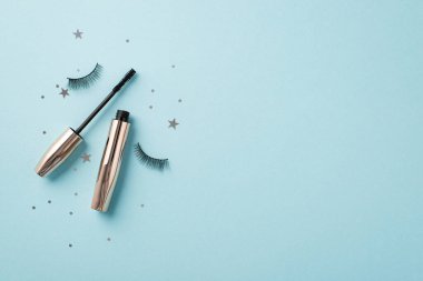 Uydurma konsept. Üst görünüm fotoğraf sahte kirpiklerin maskara ve yıldız şekilli konfeti izole edilmiş pastel mavi arka planda kopyalanmış