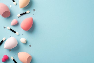 Makyaj güzellik konsepti. Farklı renk güzellik mikserlerinin üst görünümü göz blenderleri aplikatör fırçaları ve izole edilmiş pastel mavi arkaplan üzerinde yıldız şekilli konfeti