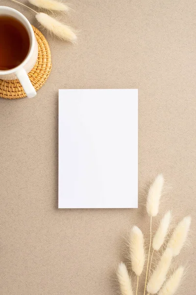 Kağıt kart, laguru çiçekleri ve bej arka planda servis paspası üzerinde çay fincanının dikey resmi.