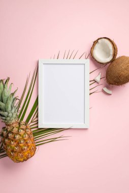 Yaz tatili konsepti. Üst görünüm beyaz fotoğraf çerçevesi dikey fotoğraf tropikal meyve hindistan cevizi ananas ve palmiye yaprakları izole edilmiş pastel pembe arka plan