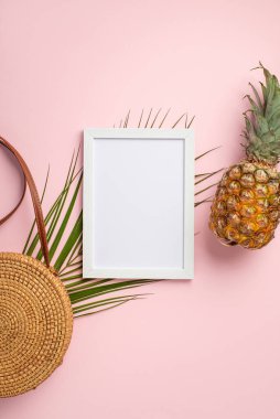 Yaz tatili kavramı. Beyaz çerçeve ananas yuvarlak ananas çantasının dikey üst görüntüsü ve izole edilmiş pastel pembe arka planda boş alan içeren palmiye yaprakları
