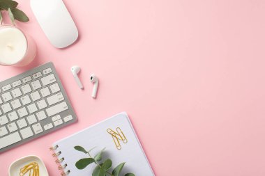 İş konsepti. Çalışma alanı klavye bilgisayar fare kablosuz kulaklıklar üst görünüm fotoğrafı izole edilmiş pembe arkaplan üzerinde not defteri mumu ve okaliptüs klipleri