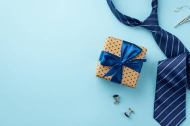 Babalar Günü konsepti. Mavi saten papyon kravat, kol düğmeleri ve mavi kravat ile izole edilmiş pastel mavi arka planda polka nokta hediye kutusunun üst görünümü