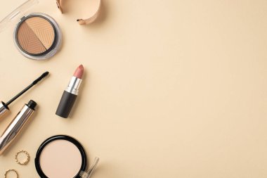 Makyaj konsepti. Palet altın yüzüklerin, bilezik rimel rujlarının ve pastel bej arkaplandaki sıkıştırılmış pudranın fotosu.