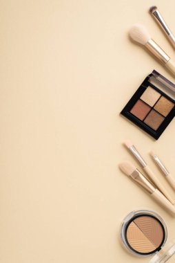Makyaj konsepti. Makyaj fırçalarının dikey üst görüntüsü allık ve göz falı paleti pastel bej arka planda ve telif alanı ile