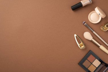 Makyaj konsepti. Göz fotografı paleti altın tokalar tırnak cilası ve makyaj fırçaları izole edilmiş kahverengi arka planda
