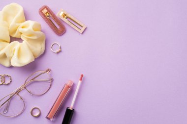 Güzellik konsepti uydur. Gözlüklü, pembe dudak parlatıcı altın yüzükler ve izole edilmiş mor arka planda boş alan olan iki toka.