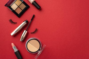 Makyaj güzellik konsepti. Göz falı şekillendiren ruj fotoğrafının üst görüntüsü sahte kirpik, rimel ve tırnak cilası ile izole edilmiş kırmızı arkaplan