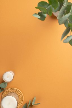 Üst görünümde çalışma alanı mumlarının dikey fotoğrafı rattan servis paspası ve vazo üzerinde okaliptüs ile izole edilmiş turuncu arkaplan ve boş alan