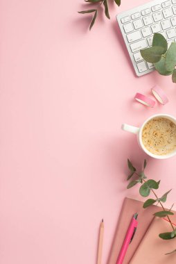 İş konsepti. İş yeri klavyesi kahve fincanının dikey resmi. Pembe not defteri yapıştırıcı bant ve boş arkaplan üzerine okaliptüs.