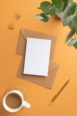 Çalışma alanı kâğıdının üstündeki çalışma alanı kağıdının dikey fotoğrafı altın renkli ataçlar, rattan servis paspası ve vazo üzerinde boş arkaplan ve izole edilmiş turuncu arkaplan üzerinde okaliptüs bulunan kahve tokaları.