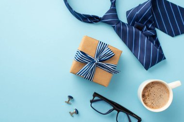 Babalar Günü konsepti. El işi kâğıdı hediye kutusunun üst görüntüsü. Üzerinde kurdele, fiyonk, kahve fincanı, kol düğmesi ve mavi kravat var.