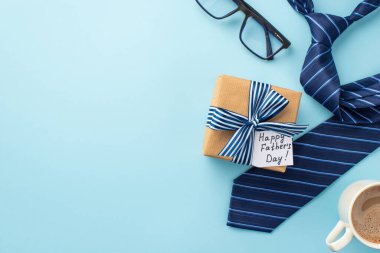 Babalar Günü konsepti. El işi kağıt hediye kutusu, kurdele yayı, kahve bardakları ve mavi kravat, izole edilmiş pastel mavi arka plan, boş alan.
