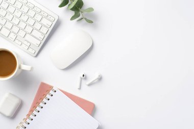 İş konsepti. İşyeri klavyesinin en iyi görüntüsü bilgisayar faresi okaliptüs fincan kablosuz kulaklık ve izole beyaz arka planda pembe not defterleri.