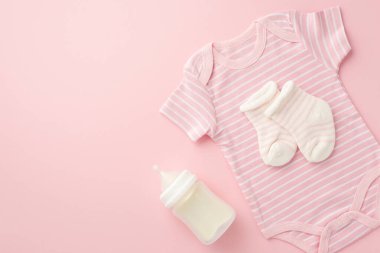 Bebek aksesuarları konsepti. Üst görüntüde pembe vücut giysisi çorapları ve şişe izole edilmiş pastel pembe arka plan ve kopyalanmış alan