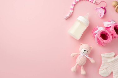 Bebek aksesuarları konsepti. Pembe patik çorapların üst görüntüsü oyuncak bebek emziği, ahşap zincir çıngırak ve şişe ve kopyalanmış pastel pembe arka plan.