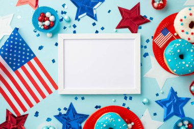 4 Temmuz konsepti. Fotoğraf çerçevesi yıldızlarının en üst görüntüsü ulusal bayraklar konfeti kağıdı şeker kalıpları ve izole edilmiş pastel mavi arka planda kaplanmış çöreklerle kaplı tabaklar boş alan