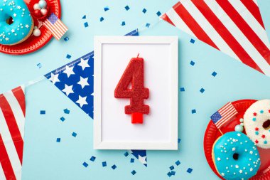 4 Temmuz konsepti. 4 numaralı mumlu fotoğraf çerçevesinin en üstteki fotoğrafı ulusal bayrak konfetisi ve izole edilmiş pastel mavi arka planda çörekli ve şekerli tabaklar.