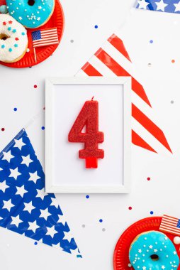 4 Temmuz konsepti. Üst görünüm fotoğraf çerçevesi 4 numara mum ulusal çelenk plakalı jöleli donutlar ve izole beyaz arka planda konfeti
