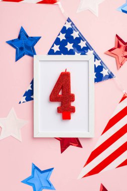 ABD Bağımsızlık Günü konsepti. Ulusal bayrağın üzerinde 4 numaralı mum bulunan fotoğraf çerçevesinin dikey üst görüntüsü ve izole edilmiş pastel arkaplandaki yıldızlar