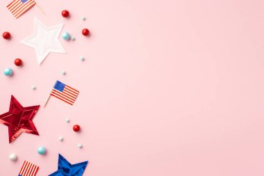 ABD Bağımsızlık Günü konsepti. Ulusal bayraklı yıldızların ve izole edilmiş pastel pembe arka plandaki dağınık şekerlerin fotosu.