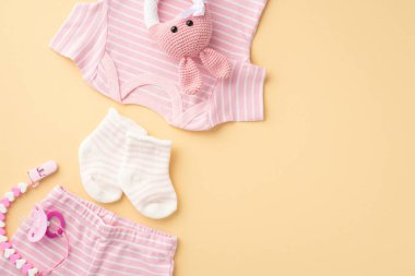 Bebek kıyafetleri konsepti. Pembe gömlekli külot, daha yumuşak zincir ve izole edilmiş bej arka planda örülmüş tavşan çıngırağı oyuncağı.