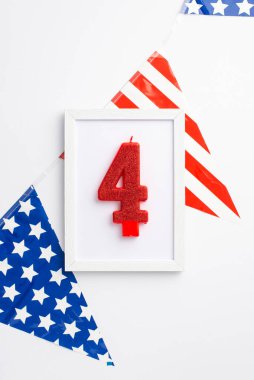 ABD Bağımsızlık Günü konsepti. 4 numaralı mum ve izole edilmiş beyaz arka planda ulusal bayrak çelengi bulunan fotoğraf çerçevesinin üst görünümü