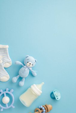 Bebek aksesuarları konsepti. Süt şişesinin dikey fotoğrafı. Oyuncak bebek çorapları. Tahta çıngırak ve bebeğin kuklası.