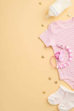 Bebek aksesuarları konsepti. Bebek kıyafetleri, pembe beden, küçük çoraplar, emzik zinciri ve izole edilmiş pastel bej arka planda altın yıldızlar.