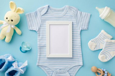 Bebek oğlan konsepti. Fotoğraf çerçevesi mavi vücut giysisi çoraplar örgü oyuncak süt şişesi tahta çıngıraklı oyuncak ayakkabılar ve izole edilmiş pastel mavi arka planda emzik.