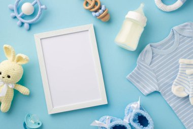 Bebek oğlan konsepti. Fotoğraf çerçevesinin en üstteki fotoğrafı örülmüş oyuncak oyuncak mavi gömlek çoraplar süt şişesi çıngıraklı ayakkabılar ve bebeğin mankeni boş mavi arka planda.