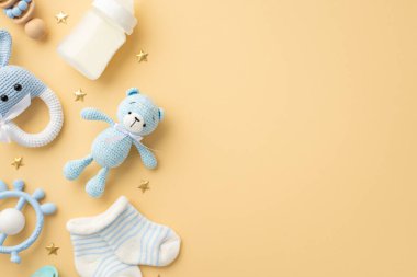 Bebek aksesuarları konsepti. Örgü örülmüş tavşan çıngırak oyuncak oyuncak oyuncak oyuncak oyuncak oyuncak süt şişesi küçük çoraplar ve izole edilmiş pastel bej arka planda altın yıldızlar.