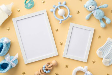 Bebek oğlan konsepti. İki fotoğraf çerçevesinin üst görüntüsü mavi oyuncak ayı çıngıraklı çorap şişesi örgü botlar ve izole edilmiş pastel bej arka planda altın yıldızlar.