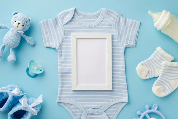 Bebek aksesuarları konsepti. Üst görüntü fotoğraf çerçevesi mavi vücut giysisi çoraplar örülmüş oyuncak ayı şişesi bağcıkları ve izole edilmiş pastel mavi arka planda emzik boş alan