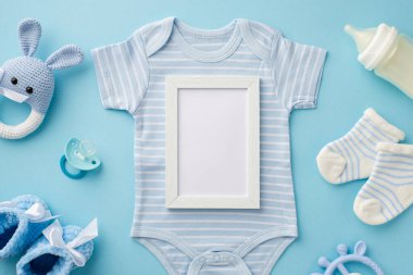 Bebek aksesuarları konsepti. En üstteki fotoğraf çerçevesi mavi vücut giysisi çoraplar örülmüş oyuncak oyuncak şişesi bağlama botları ve izole edilmiş pastel mavi arka planda boş alan