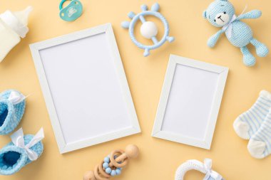 Bebek aksesuarları konsepti. İki fotoğraf çerçevesinin üst görüntüsü mavi oyuncak ayı çıngıraklı çorap, süt şişesi ip bağlayıcı ve izole edilmiş pastel bej arka plan üzerine örülmüş ayakkabılar boş alan