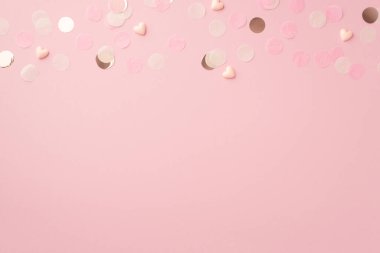 Pembe kalplerin ve parlak konfetilerin izole edilmiş pastel pembe arka plandaki boş alandaki en iyi görüntüsü.